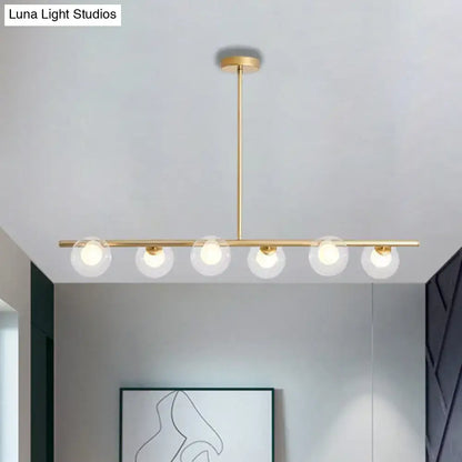 Gold-toned DecorBites™ modern pendant light with five clear glass globe light bulbs in a linear dining table design