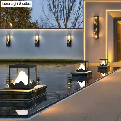 Modern black and gold cube solar led outdoor light with illuminated mountain design floating on reflective water surface