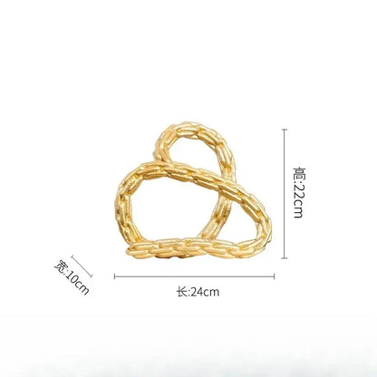 Modern black and golden knot chain sculpture with a gold-colored braided metal hair clip featuring a golden knot chain design