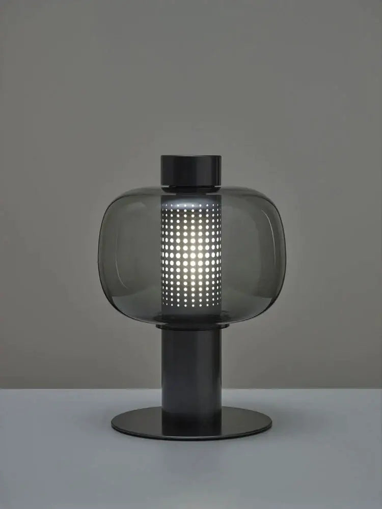 Modern black and gray decorbites glass table light with a translucent perforated body and sleek metal base for bedside use