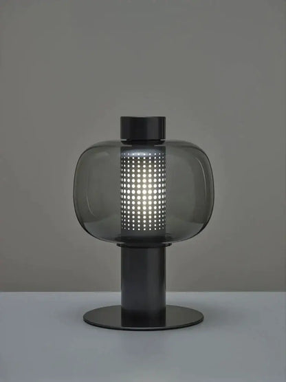 Modern black and gray decorbites glass table light with a translucent perforated body and sleek metal base for bedside use