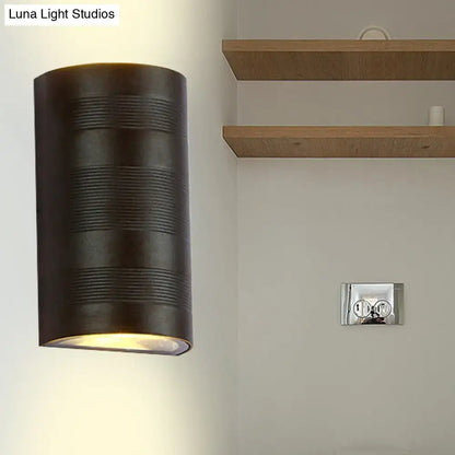 Dark bronze cylindrical wall lamp with horizontal ribbed texture and warm white diffused lighting for outdoor use