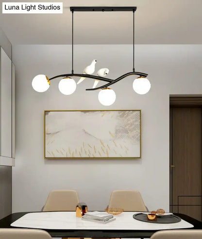 Modern black metal pendant light with three white glass shades and two white dove sculptures for linear island use