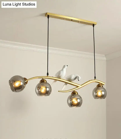 Modern black and white bird linear island pendant light with gold-toned metal arm and three smoked glass shades