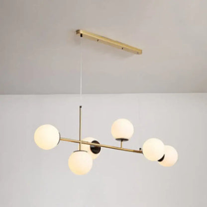 Modern black and white bird linear island pendant light featuring a brass fixture with five frosted glass shades