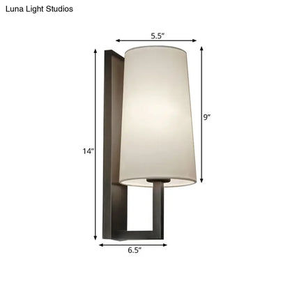 Modern black and white fabric wall lamp with matte black metal frame and off-white cylindrical shade for bedroom lighting