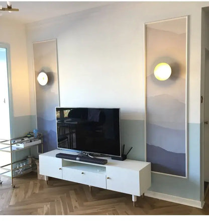 White minimalist tv stand with sleek legs and glass drawer fronts complementing decorbites golden glass ball wall sconce