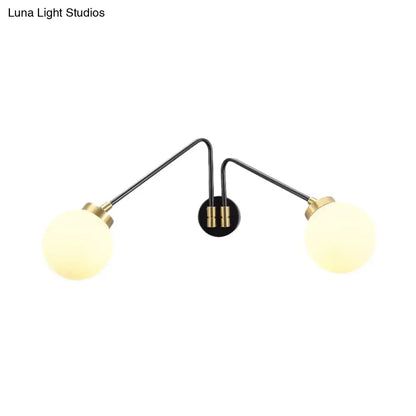 Modern black and brass double-arm wall lamp with milk glass frosted globe shades for bedroom decor