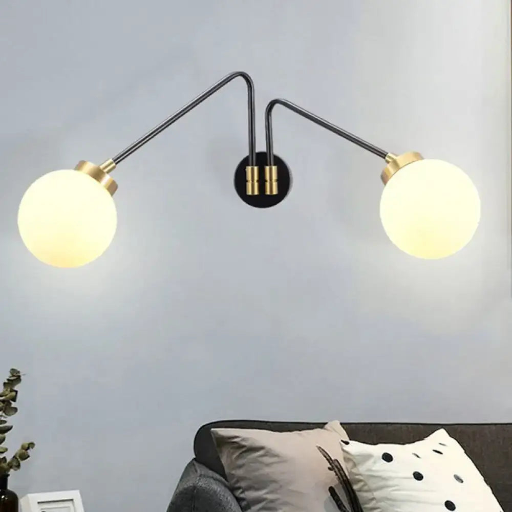 Modern black and brass wall lamp with double arms and frosted milk glass globe shades for bedroom sconce lighting