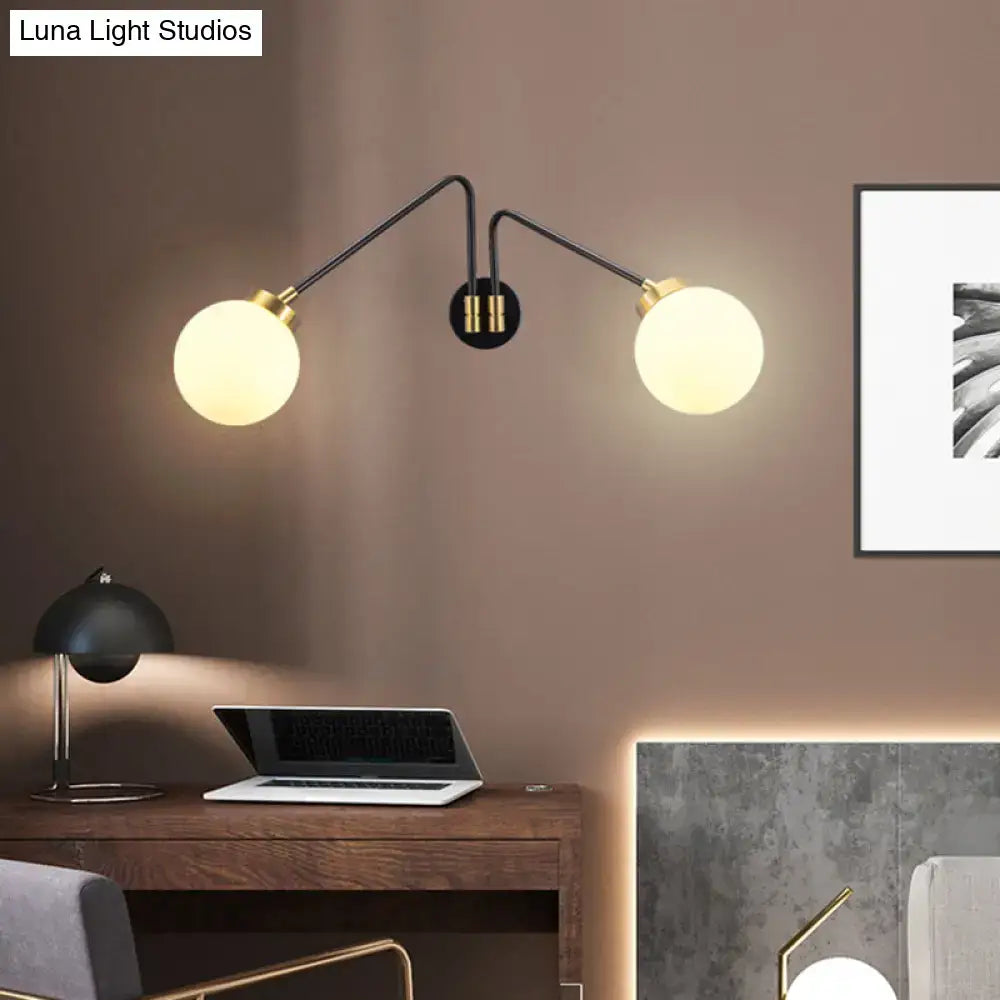 Modern black and brass wall lamp with double-arm design and milk glass spherical shades for bedroom sconce use