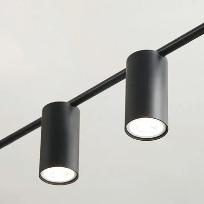 Modern black and brass minimalist dining room linear pendant light with black cylindrical track lights and recessed led bulbs