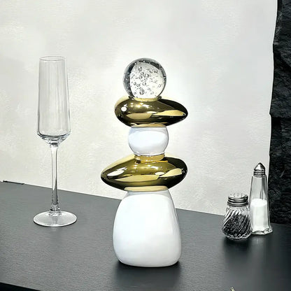 A modern black ceramic decorative crystal ball statue with stacked polished gold and white orbs and a clear glass bubble