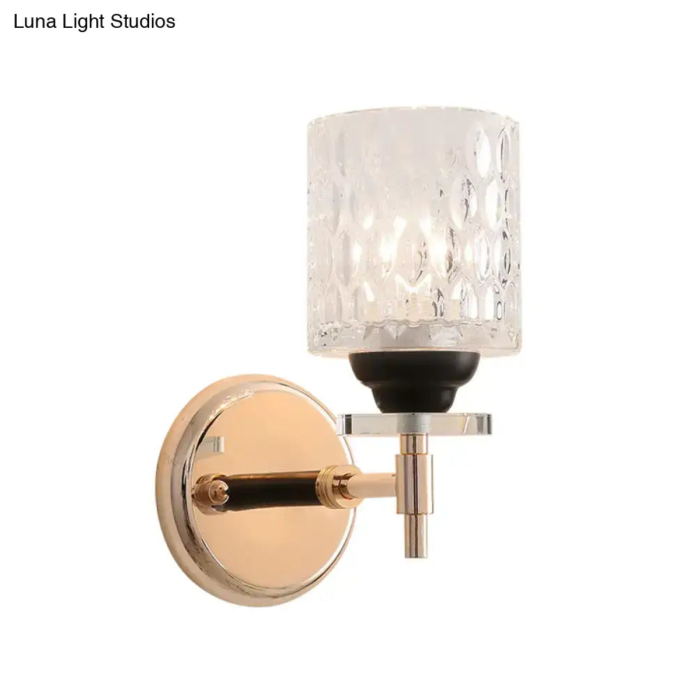 A modern wall sconce with a dimpled glass cylinder shade, black chrome and rose gold metal accents for bedroom lighting