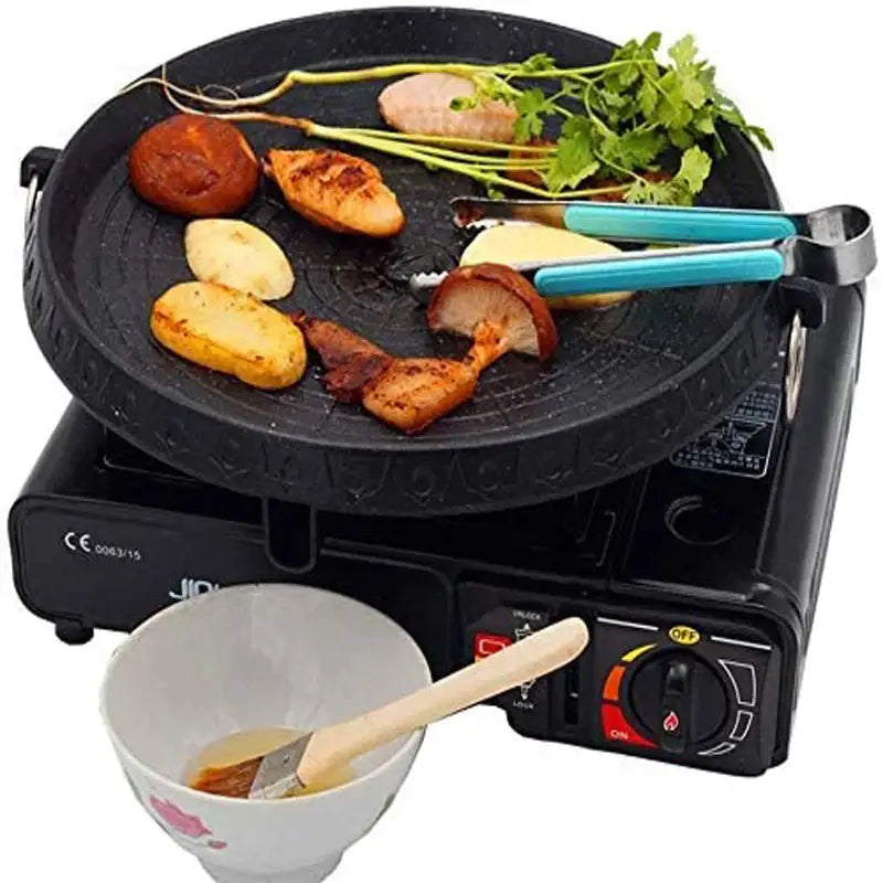 Modern black circular cast iron korean grill pan with food and blue tongs on portable gas burner decorbites korean grill
