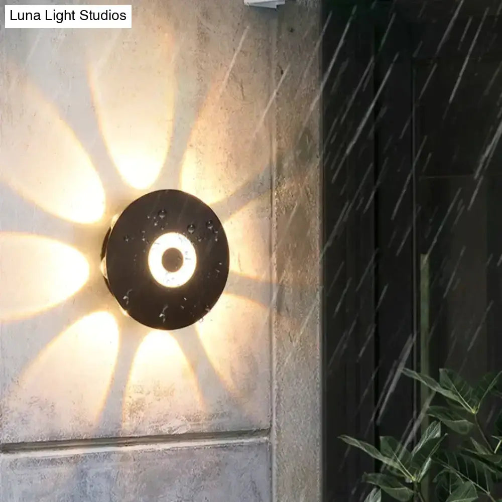 Modern black circular led outdoor wall sconce with a central ring emitting warm radial illumination for garden use