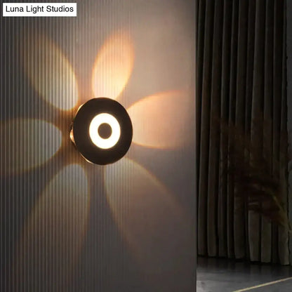 Modern black circular led outdoor wall sconce with glowing ring and petal-shaped light patterns for outdoor wall use