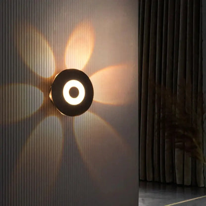 Modern black circular led outdoor wall sconce with glowing ring and radiating light beams for outdoor wall use