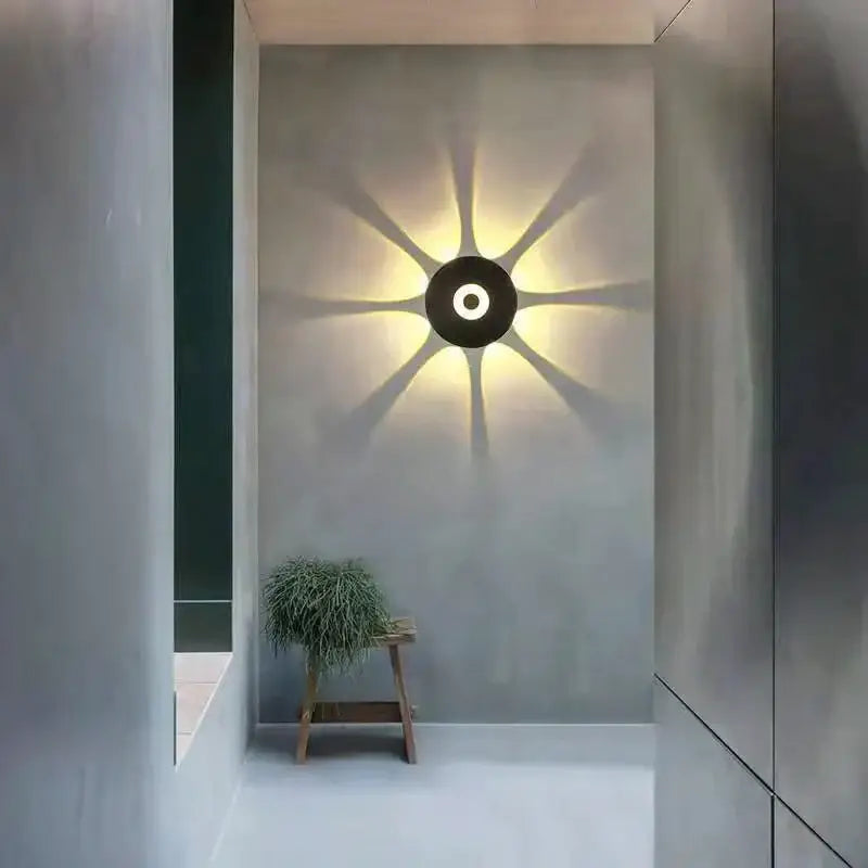 Modern black circular led outdoor wall sconce casting warm radiating light beams for garden outdoor wall lighting