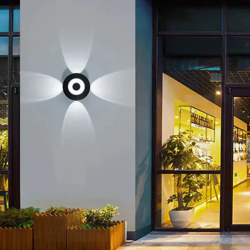 Modern black circular led outdoor wall sconce with four radiant light beams for outdoor wall garden lighting