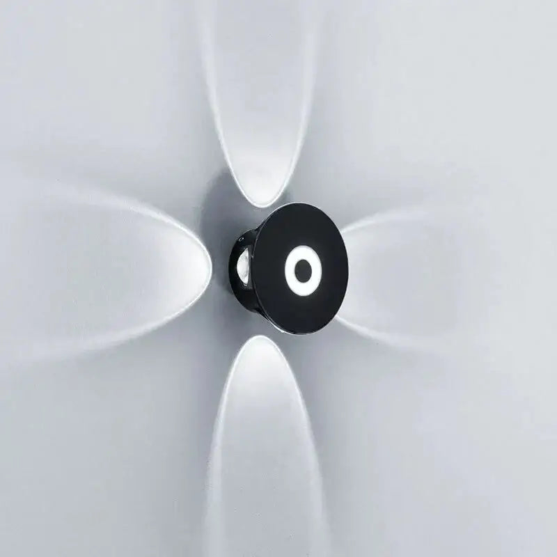 Modern black circular led outdoor wall sconce with frosted white diffusers radiating on an outdoor wall sconce garden light