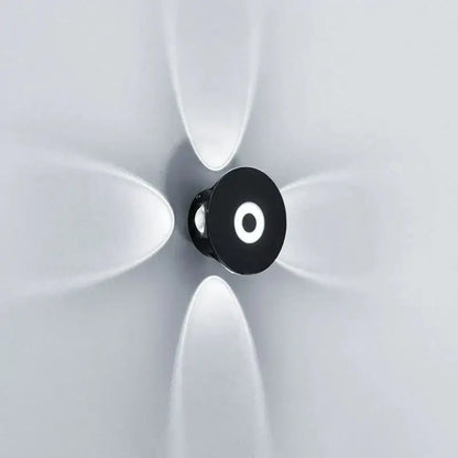 Modern black circular led outdoor wall sconce with frosted white diffusers radiating on an outdoor wall sconce garden light
