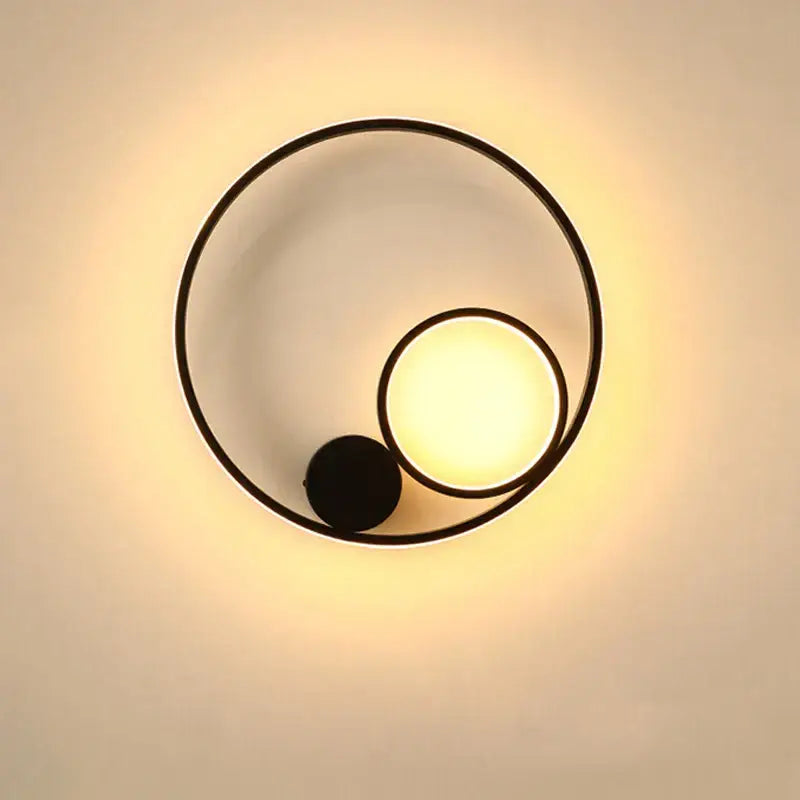 Modern black circular led wall lamp with warm glowing light and minimalist geometric design for bedroom use