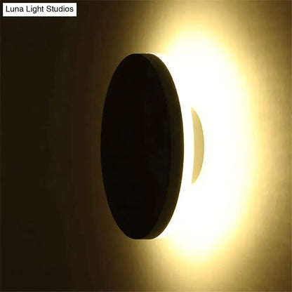 Modern black circular wall lamp with sleek minimalist design emitting warm ambient light for bedroom use