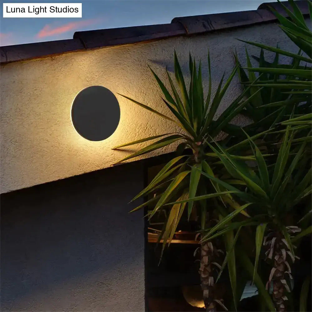 Modern black circular wall lamp with waterproof design emitting a warm glow for bedroom use