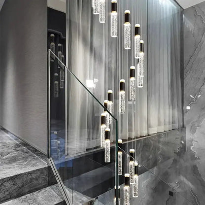 Modern black and clear decorbites crystal chandelier with cylindrical glass and black accents in sleek staircase setting