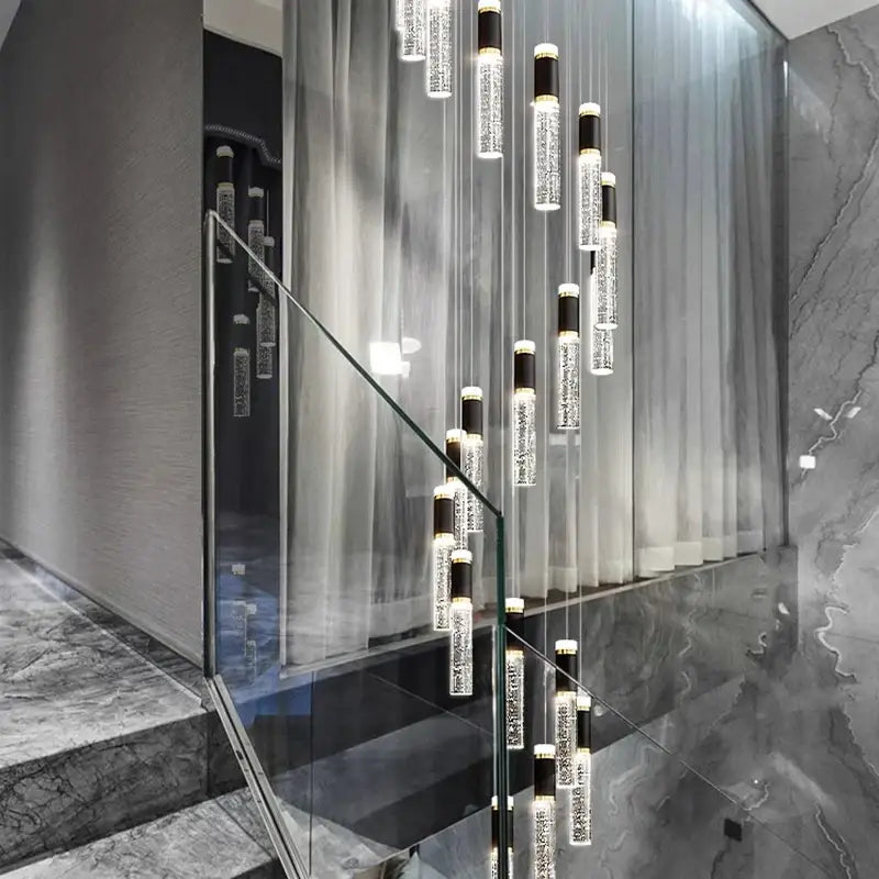 Modern black and clear decorbites crystal chandelier with cylindrical glass and black accents in sleek staircase setting
