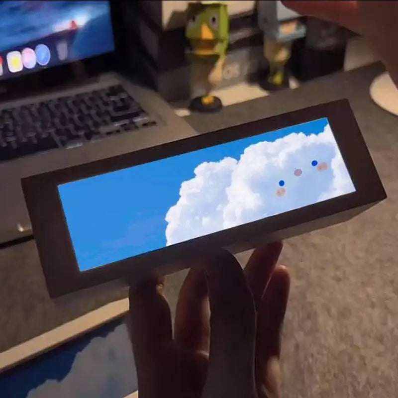 A sleek black rectangular cloud night light digital display shows a vibrant blue sky with fluffy white clouds for bedroom decor