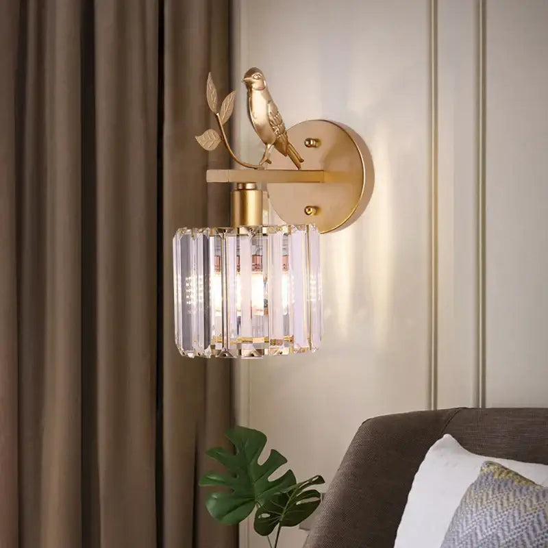Gold-toned wall lamp with decorbites crystal bird perched on branch featuring crystal bird wall prisms for bedroom decor