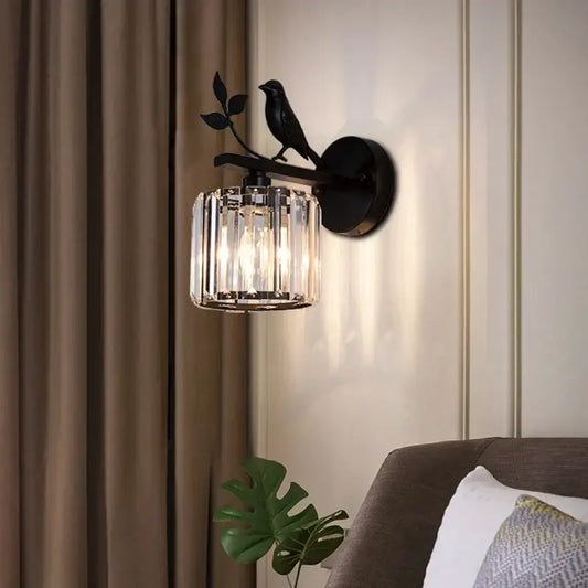 Modern black crystal bird wall lamp featuring a wrought iron sconce with a perched bird and cylindrical crystal shade