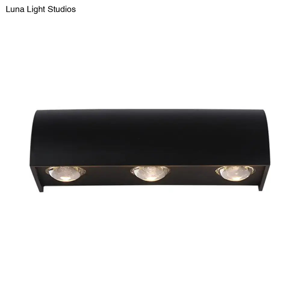 Modern black curved wall lamp with three circular recessed bulbs providing warm white minimalist led light