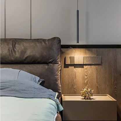 Golden metallic starburst sculpture on a beige nightstand with modern black finish cord pendant light in bedroom