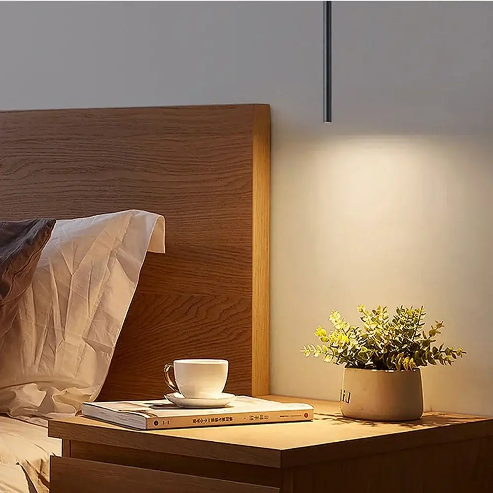Modern black cylindrical cord pendant light with slender black finish stem and warm focused lighting for bedroom