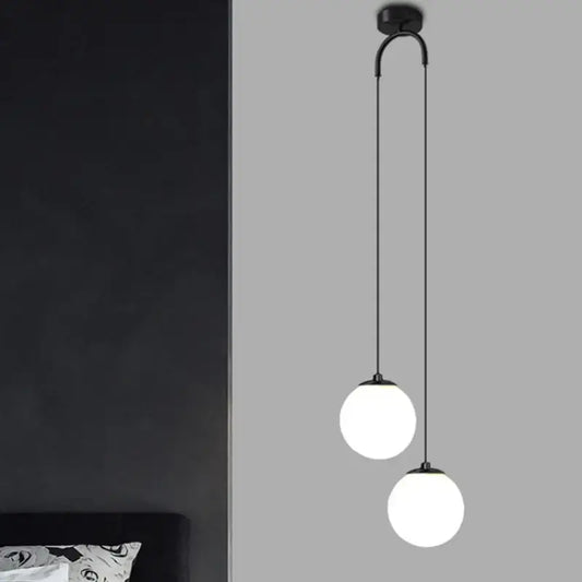 Modern black double glass ball pendant light featuring two frosted glass globes on a curved arm for bedroom ceiling