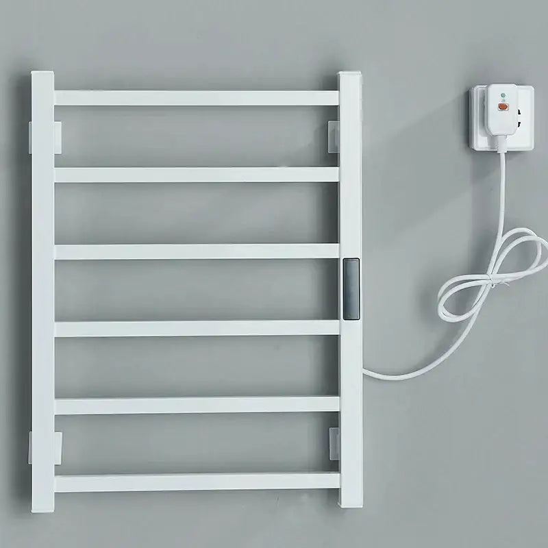 White electric towel warmer with sleek minimalist design and matching power cord plugged into outlet for bathroom use