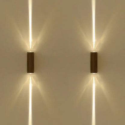 Two sleek modern wall lamps with a black matte finish emit warm dual vertical beams of light for hotel ambiance