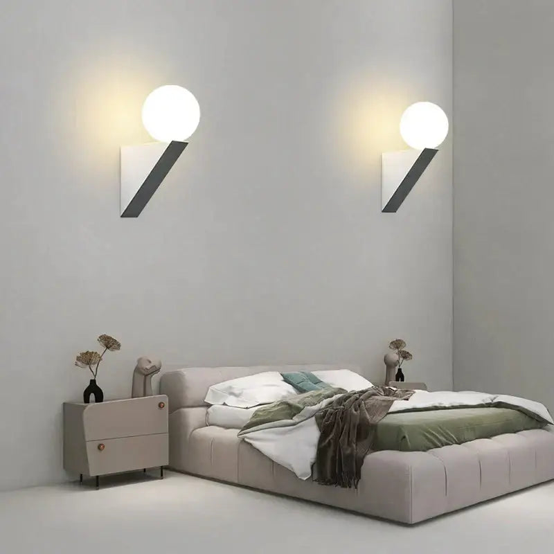 Modern black glass ball wall lamp with sleek angular black base and glowing white spherical glass shade wall sconce