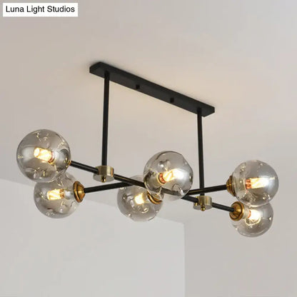 Modern black glass island pendant light featuring brass accents and six clear glass globe bulbs for dining room use