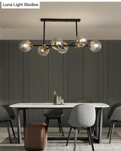 Modern black island pendant light with brass accents and clear glass globe bulbs for dining room lighting