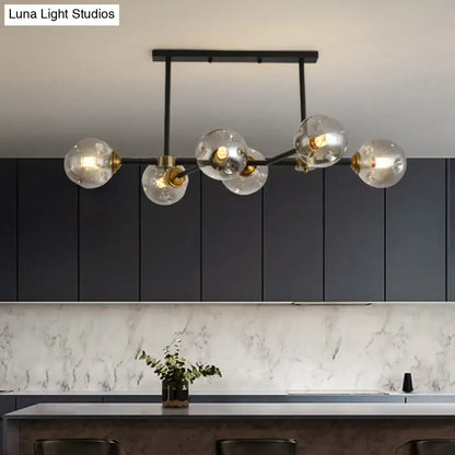 Modern black island pendant light with five clear glass globe bulbs and brass accents for dining room lighting
