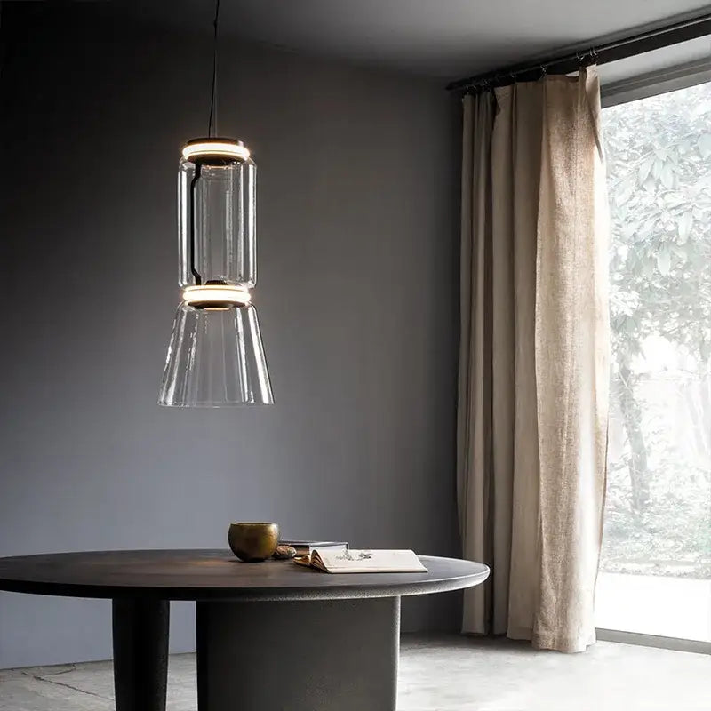 Modern black glass led pendant light with sleek cylindrical design and warm metallic accents for dining room use