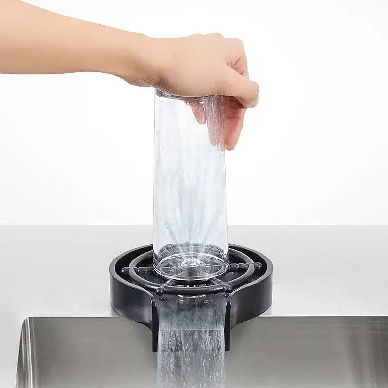 Clear glass pitcher being rinsed in a modern black glass rinser sink drip tray for automatic cup washing
