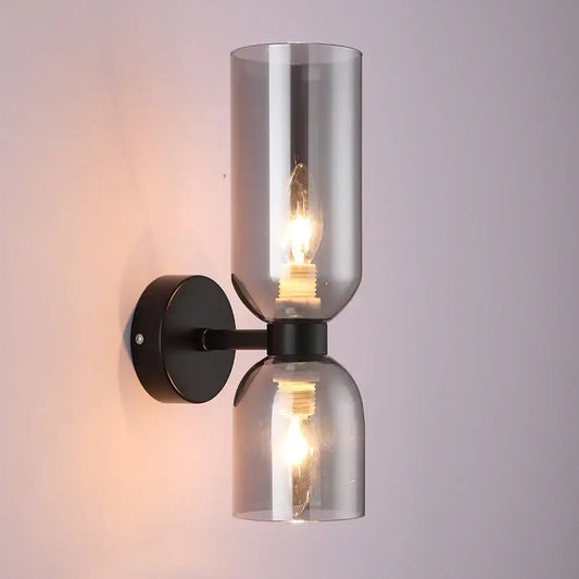 Modern black metal wall lamp with two smoked glass shades and exposed filament bulbs for bedroom use