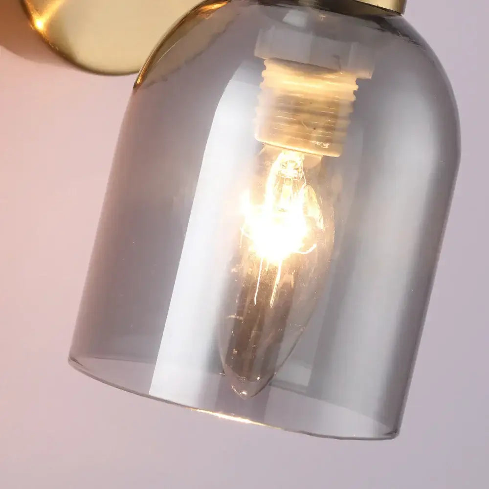 Modern black glass shade wall lamp with smoked glass shade and brass fixture featuring an exposed filament bulb