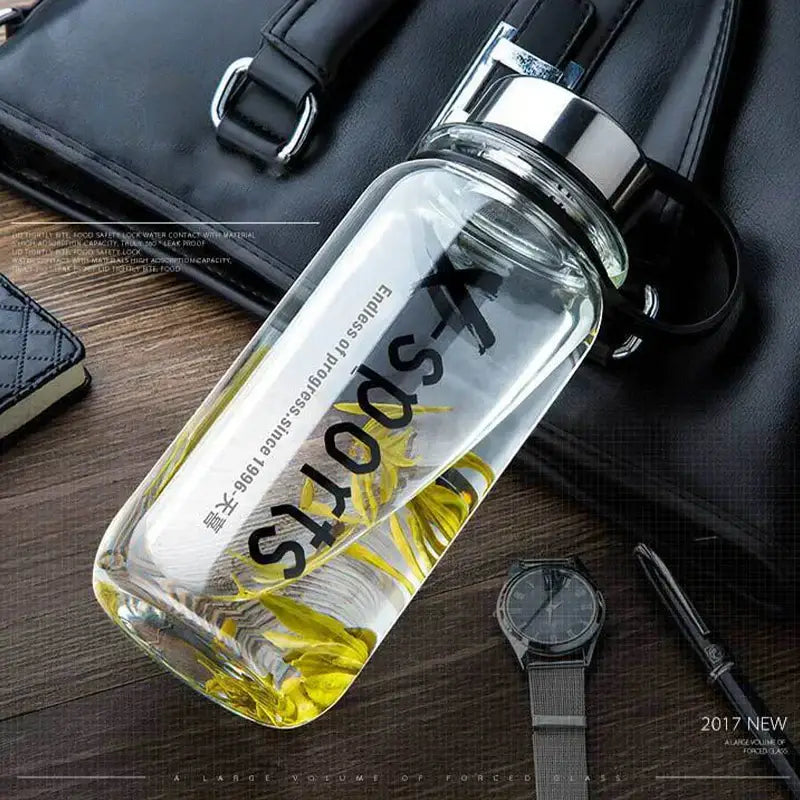 Modern black glass tea bottle with silver lid and black sports lettering containing yellow flowers for decorbites glass tea use