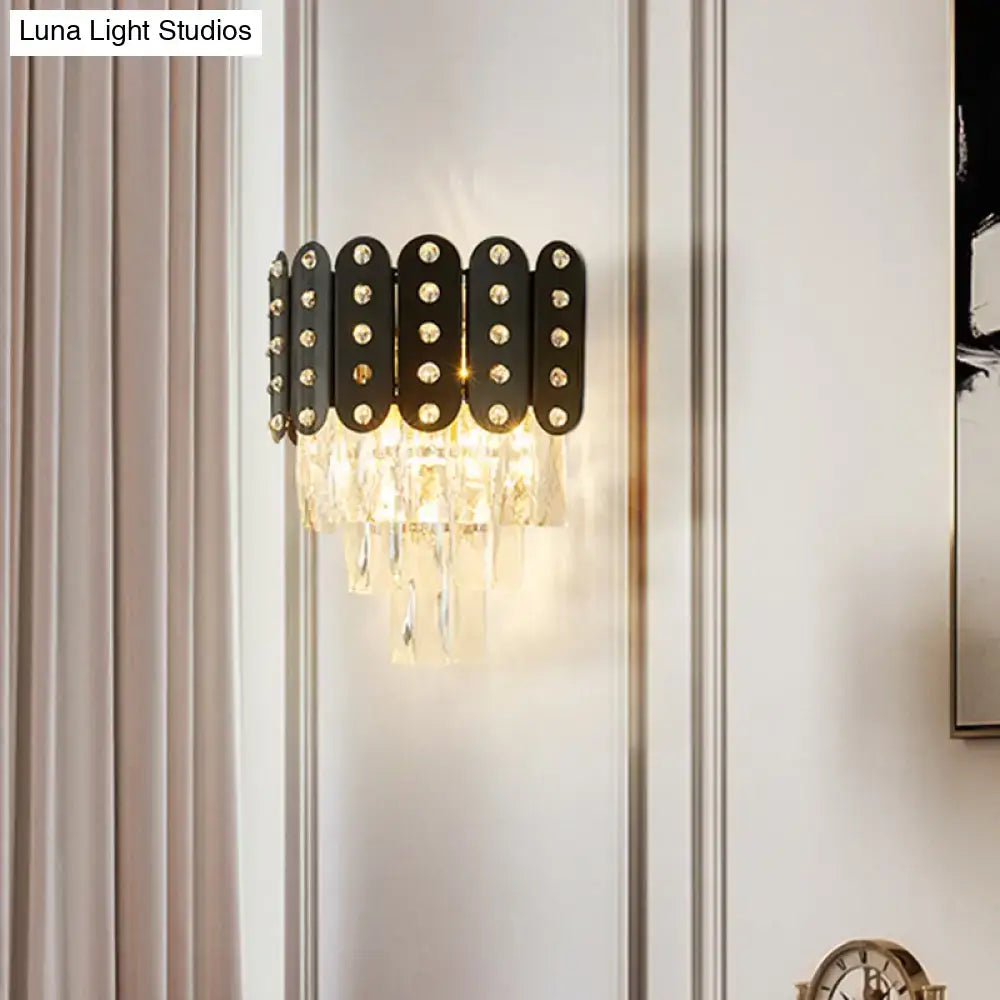 Modern black and gold 3-tiered wall-mounted light with clear faceted crystal droplets and gold-toned studs for living rooms