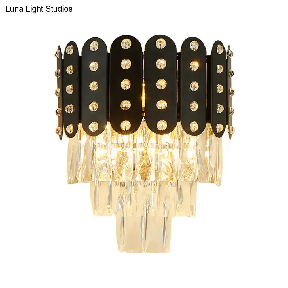 Modern black and gold 3-tiered wall-mounted light with clear faceted crystal accents and cascading glass prisms